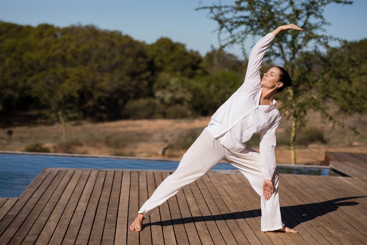 A woman practicing yoga on an outdoor wooden deck