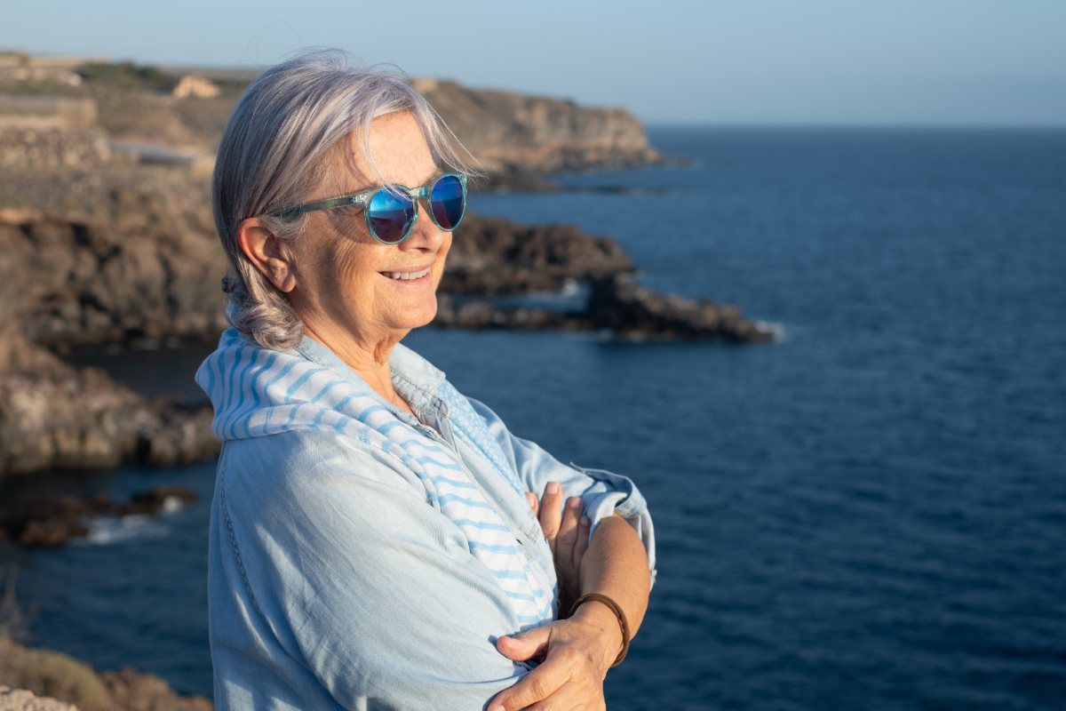 A woman with folded arms enjoying a coastal view
