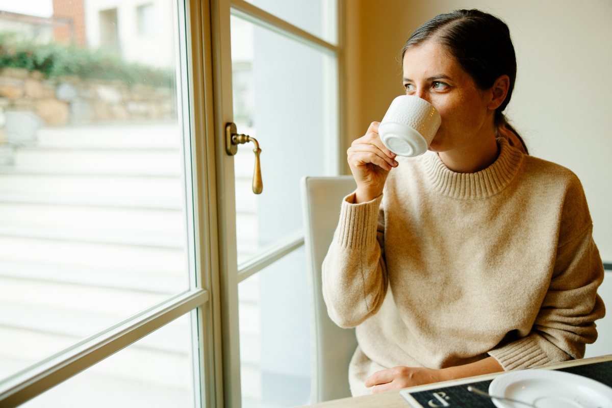 A thoughtful woman in a cozy sweater with a cup of coffee